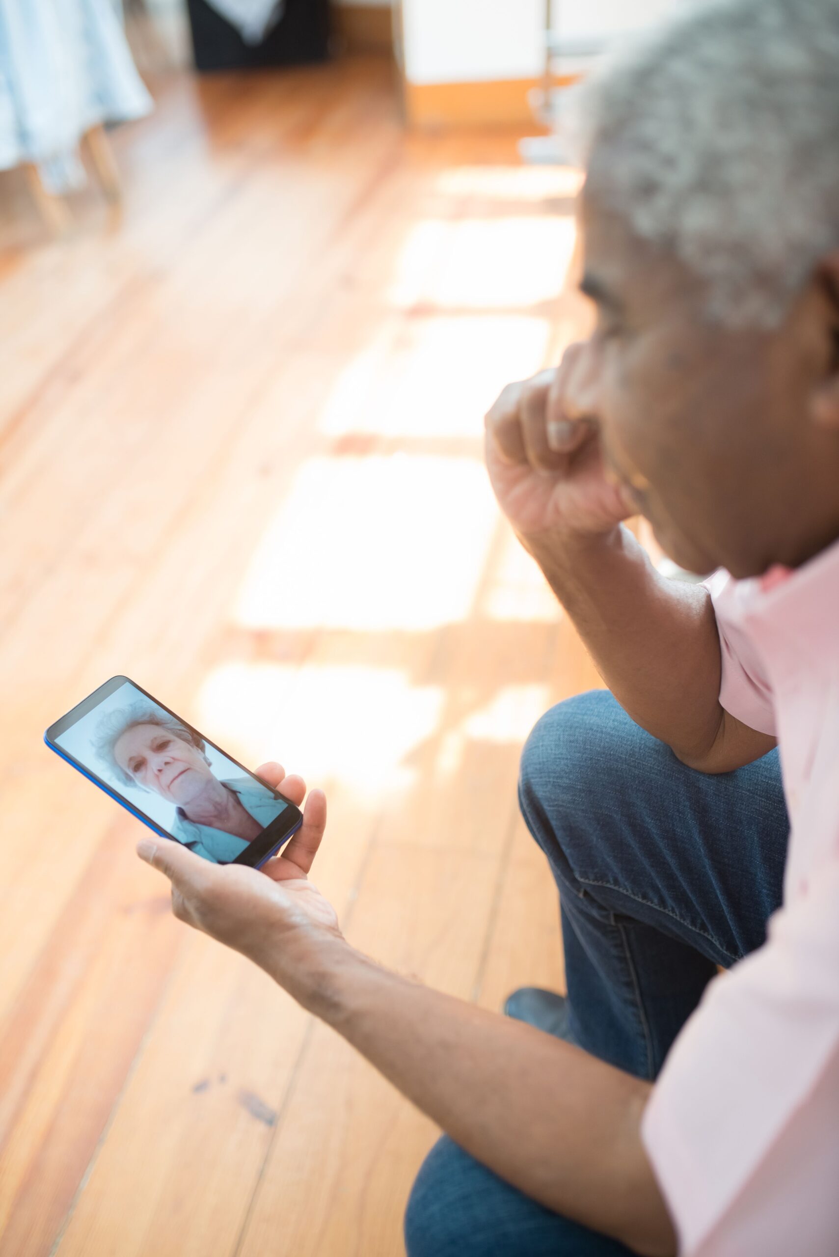 A senior man video calling on a smartphone indoors.