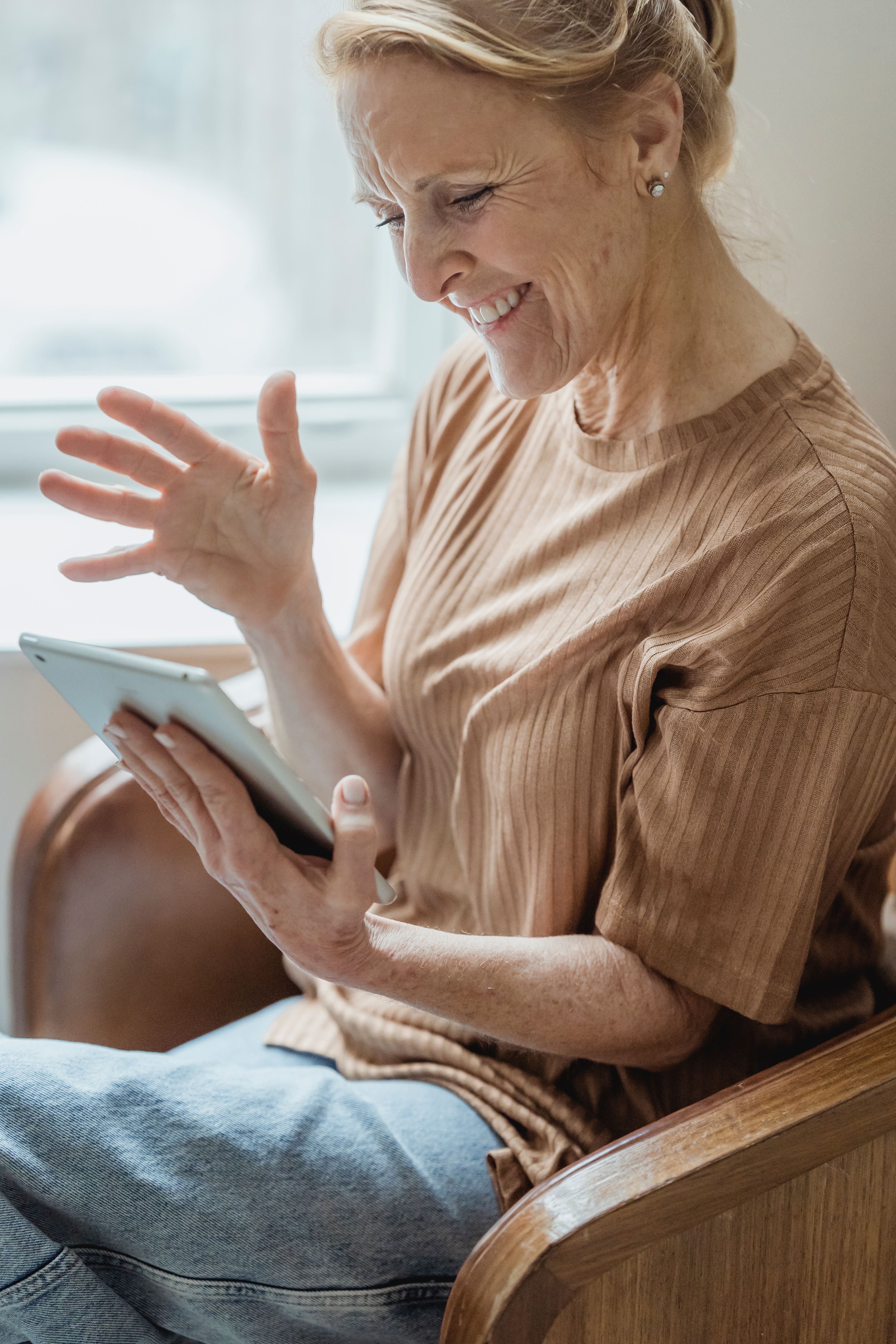 A smiling senior woman enjoying a video call on her tablet at home.